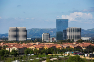 Irvine California skyline with desert mountains of blue and tan with red roofed buildings infront of skyscrapers 