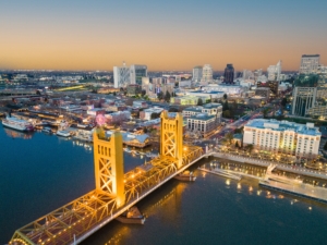 golden Sacramento bridge over the water with a city scape behind it at sunset 